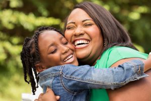 African American mother and daughter laughing and hugging each other