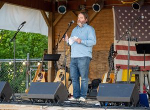 Nick Ward, a Children's Home Society of Virginia adoptive father. Nick is standing on a stage at Main Line Brewery addressing a crowd during Children's Home Society of Virginia's 2023 Anniversary Celebration event.