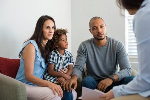 Serious couple with son in a deep conversation with family counselor.