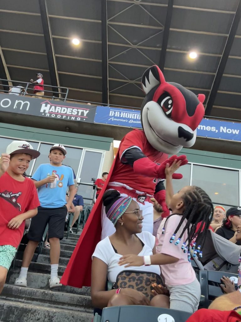 Nutsy, the Richmond Flying Squirrels mascot, is giving a young girl a high five.