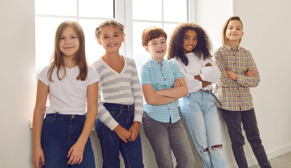 Group of happy smiling diverse children standing by the window and looking at camera.