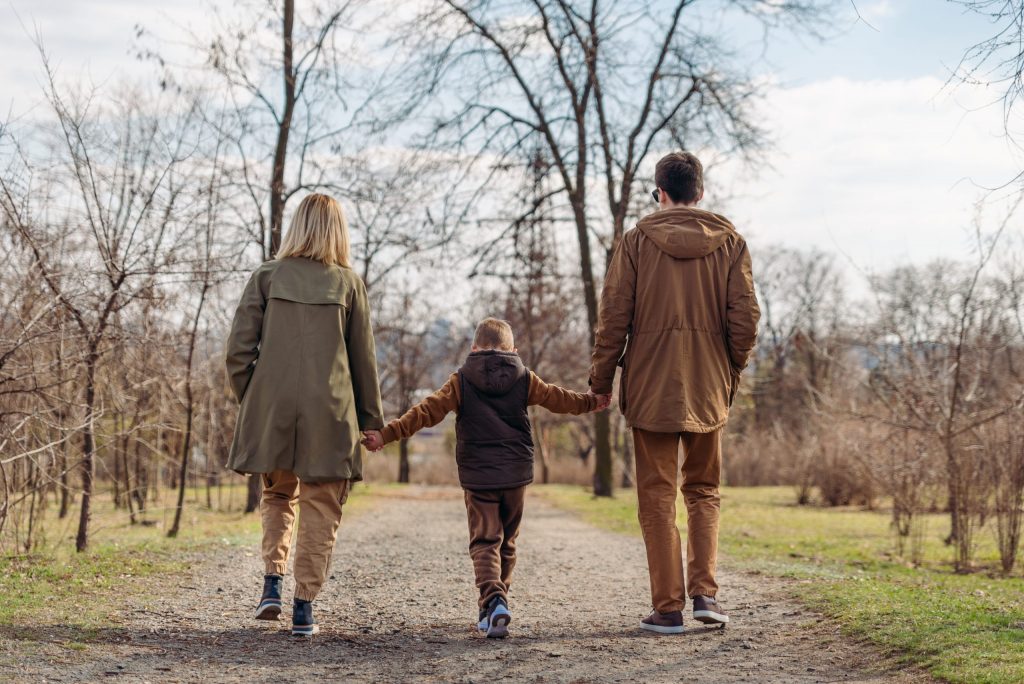 an adoptive family walking in the park holding hands. Representing why adoption matters.